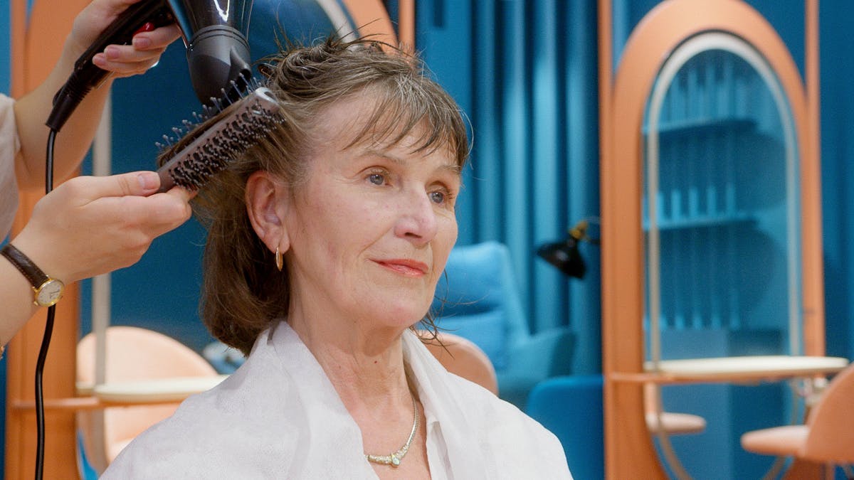 Photo by Artem Podrez A senior woman receives hairstyling and pampering in a modern salon setting.