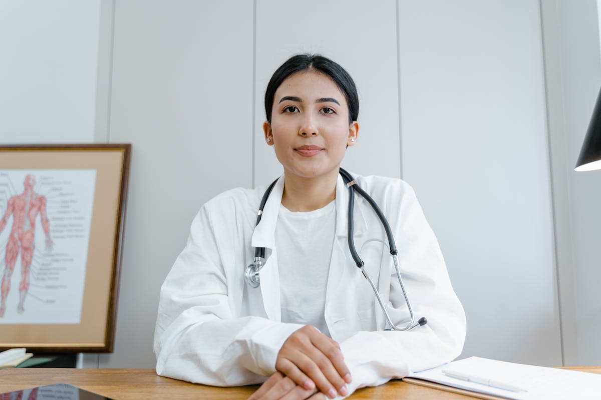 Photo by Tima Miroshnichenko A female doctor confidently sits at her desk, ready for consultation in a medical office.